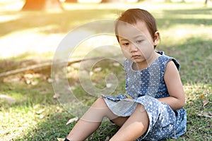 Young Little Asian kid sitting on grass outdoor park depressed and worry for distress, crying angry and afraid. Sad expression