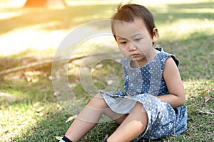 Young Little Asian kid sitting on grass outdoor park depressed and worry for distress, crying angry and afraid. Sad expression