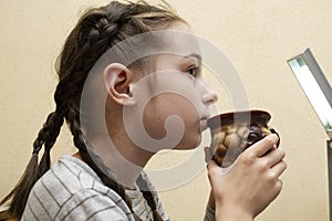 Young little baby girl drinking milk mug coffee tea hot drink. 9 years old girl drinks milk or tea from a cup