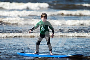 Young little boy on beach taking surfing lessons