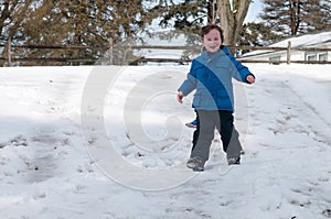 Young little boy enjoying sledding outside on a snow day