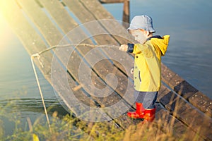 Young little boy fishing from wooden dock