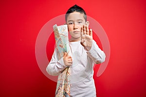 Young little boy kid looking at turist city destination map over red isolated background with open hand doing stop sign with