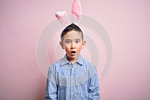 Young little boy kid wearing easter bunny ears over isolated pink background afraid and shocked with surprise expression, fear and