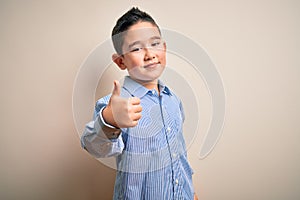 Young little boy kid wearing elegant shirt standing over isolated background doing happy thumbs up gesture with hand