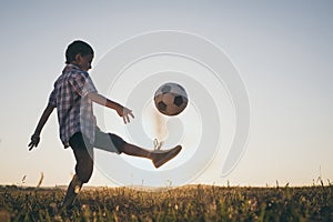 Young little boy playing in the field  with soccer ball