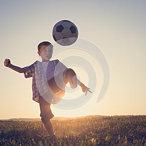 Young little boy playing in the field  with soccer ball