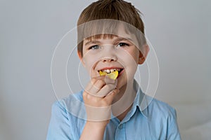 Young little caucasian child eating unhealthy potato chips on a gray background