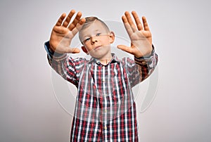 Young little caucasian kid with blue eyes wearing elegant shirt standing over isolated background doing frame using hands palms