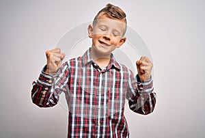 Young little caucasian kid with blue eyes wearing elegant shirt standing over isolated background very happy and excited doing