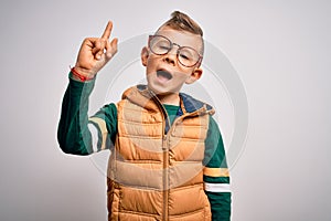 Young little caucasian kid with blue eyes wearing winter coat and smart glasses pointing finger up with successful idea