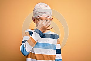 Young little caucasian kid injured wearing medical bandage on head over yellow background tired rubbing nose and eyes feeling