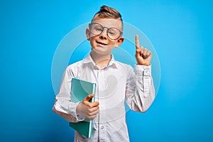 Young little caucasian student kid wearing smart glasses and holding a book from school surprised with an idea or question