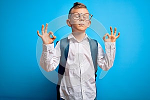 Young little caucasian student kid wearing smart glasses and school bag over blue background relax and smiling with eyes closed