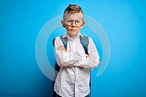 Young little caucasian student kid wearing smart glasses and school bag over blue background skeptic and nervous, disapproving