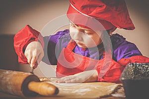 Young little chef girl with cook hat preparing sweet desert at home kitchen. Horizontal image