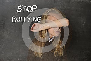 Young little cute schoolgirl scared sad covering her face and the words stop bullying text