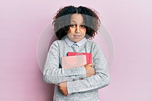 Young little girl with afro hair holding books clueless and confused expression