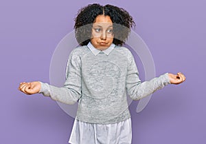 Young little girl with afro hair wearing casual clothes clueless and confused expression with arms and hands raised