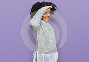 Young little girl with afro hair wearing casual clothes very happy and smiling looking far away with hand over head