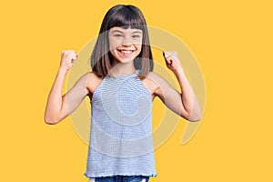 Young little girl with bang wearing casual clothes screaming proud, celebrating victory and success very excited with raised arms