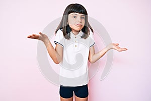 Young little girl with bang wearing sportswear clueless and confused expression with arms and hands raised