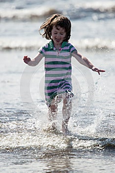 Young little girl on beach playing in the surf