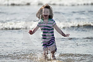 Young little girl on beach playing in the surf
