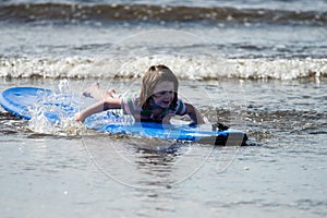 Young little girl on beach taking surfing lessons