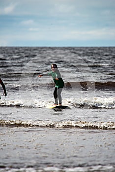 Young little girl on beach taking surfing lessons