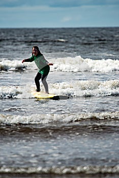 Young little girl on beach taking surfing lessons