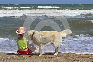 Young Little Girl And Golden Retriever Dog Sitting On The Beach.Girl Sitting Alone With Her Dog.