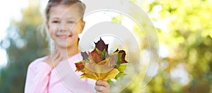 Young little girl hold fall leaves in hands. Red, gree and yellow leaf. Autumn nature outdoor city