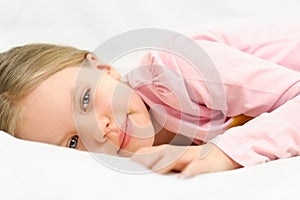 Young little girl is laying on bed with peaceful face expression