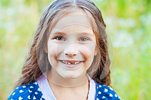 Young little girl with long hair without front tooth smiles, natural light