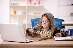 Young little girl playing chess at home