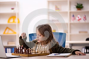 Young little girl playing chess at home