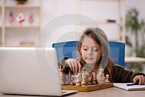 Young little girl playing chess at home