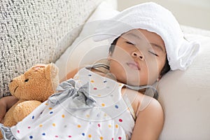 Young little girl sleeping and sick on the sofa with cooler gel