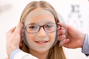 Young little girl trying glasses at the optician