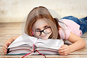 Young little girl wearing glasses and reading a book