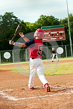 Young little league boy swings bat