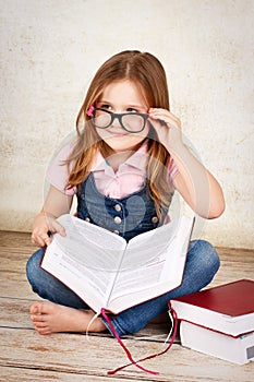 Young little nerd wearing glasses and reading a book