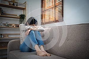 Young lonely attractive asian woman crying on couch feeling sad tired and worried suffering depression isolated at home