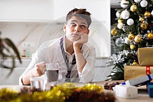 Young lonely man drinking alcohol at christmas table at home