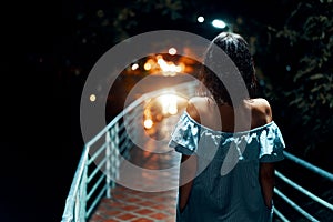 Young lonely woman walking on the bridge at night