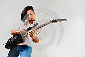 Young long haired guitarist excited playing his black electric guitar, isolated on white background