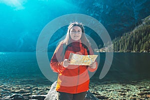 Young lost woman traveler with map and backpack points in the direction relaxing outdoor with rocky on Morskie Oko lake