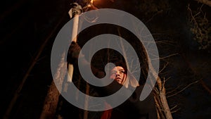 Young lost woman walking in dark winter forest with a handmade torch