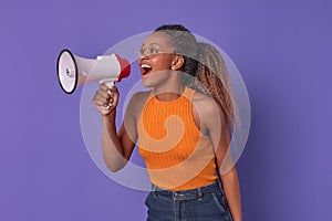 Young loud African American woman holding white megaphone stands in studio
